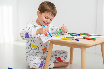 een kind die zijn inkleurbare pyjama inkleurd WITE ACHTERGROND